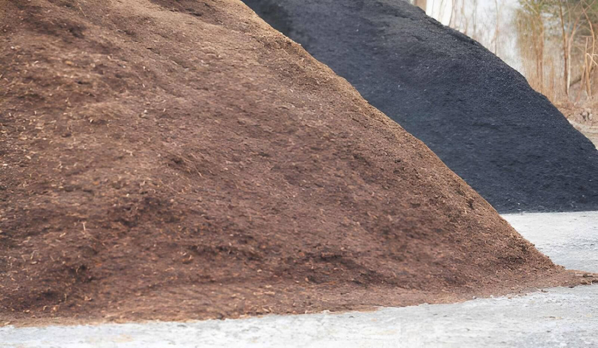Black and brown mulch piles displayed side by side for landscaping comparison.