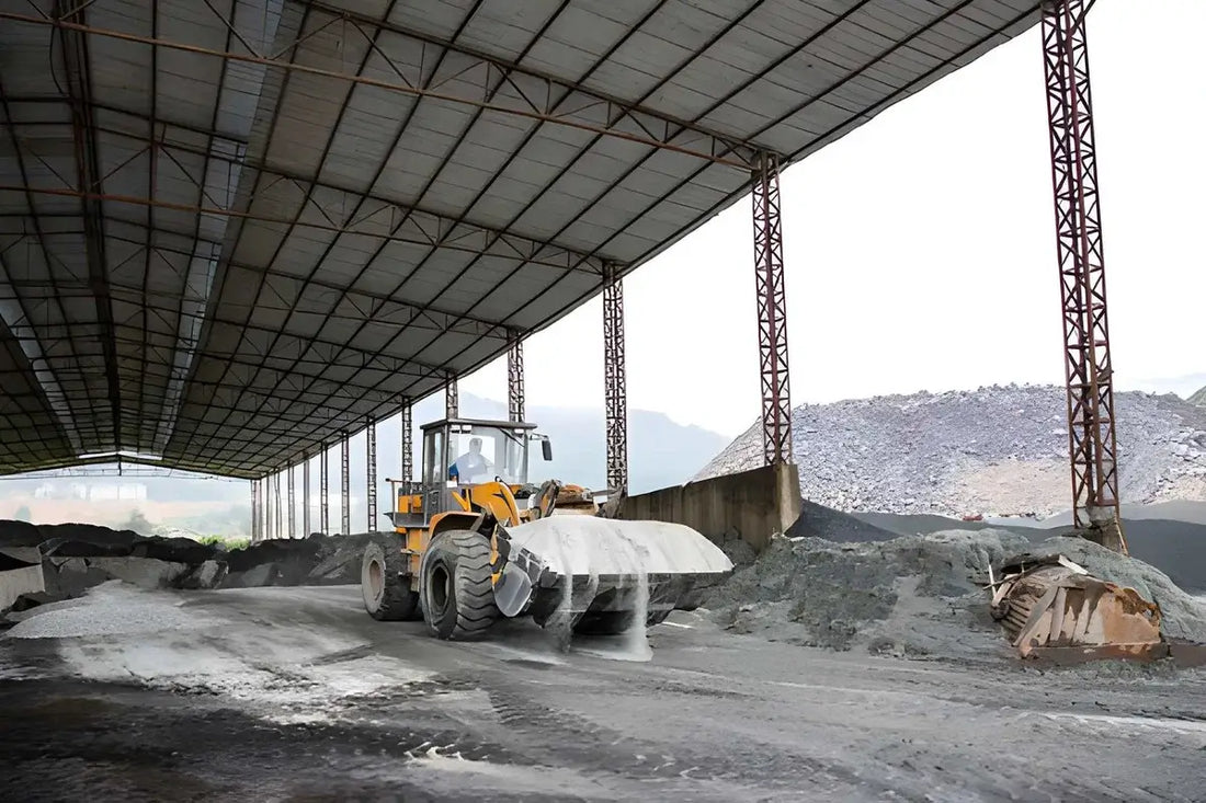 Front-end loader moving concrete sand and aggregate at a covered materials facility.
