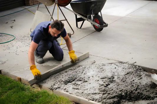 Worker smoothing fresh concrete for a residential driveway installation.